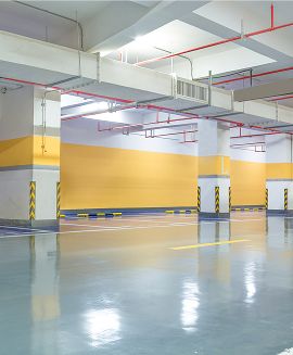 Empty multi-level indoor parking garage with yellow safety pillars and a polished epoxy floor
