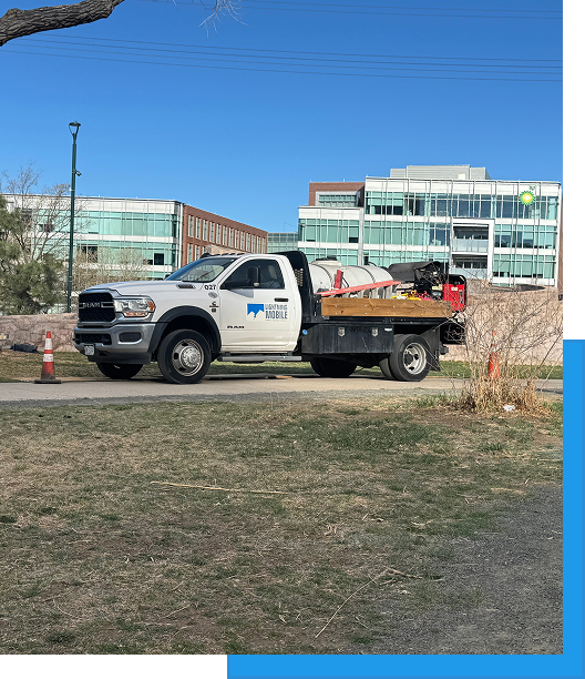 White Lightning Mobile service truck with flatbed equipment parked on grass near office buildings, with traffic cones on the sidewalk.