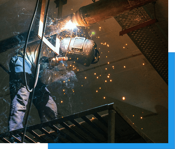 Welding New 2 Welder performing overhead pipe welding in an industrial facility, sparks flying below